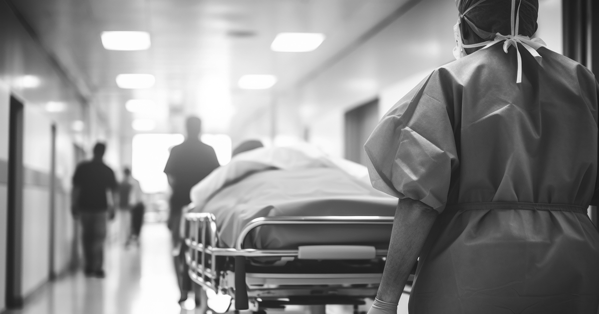 Image of a person pushing a hospital bed down a corridore